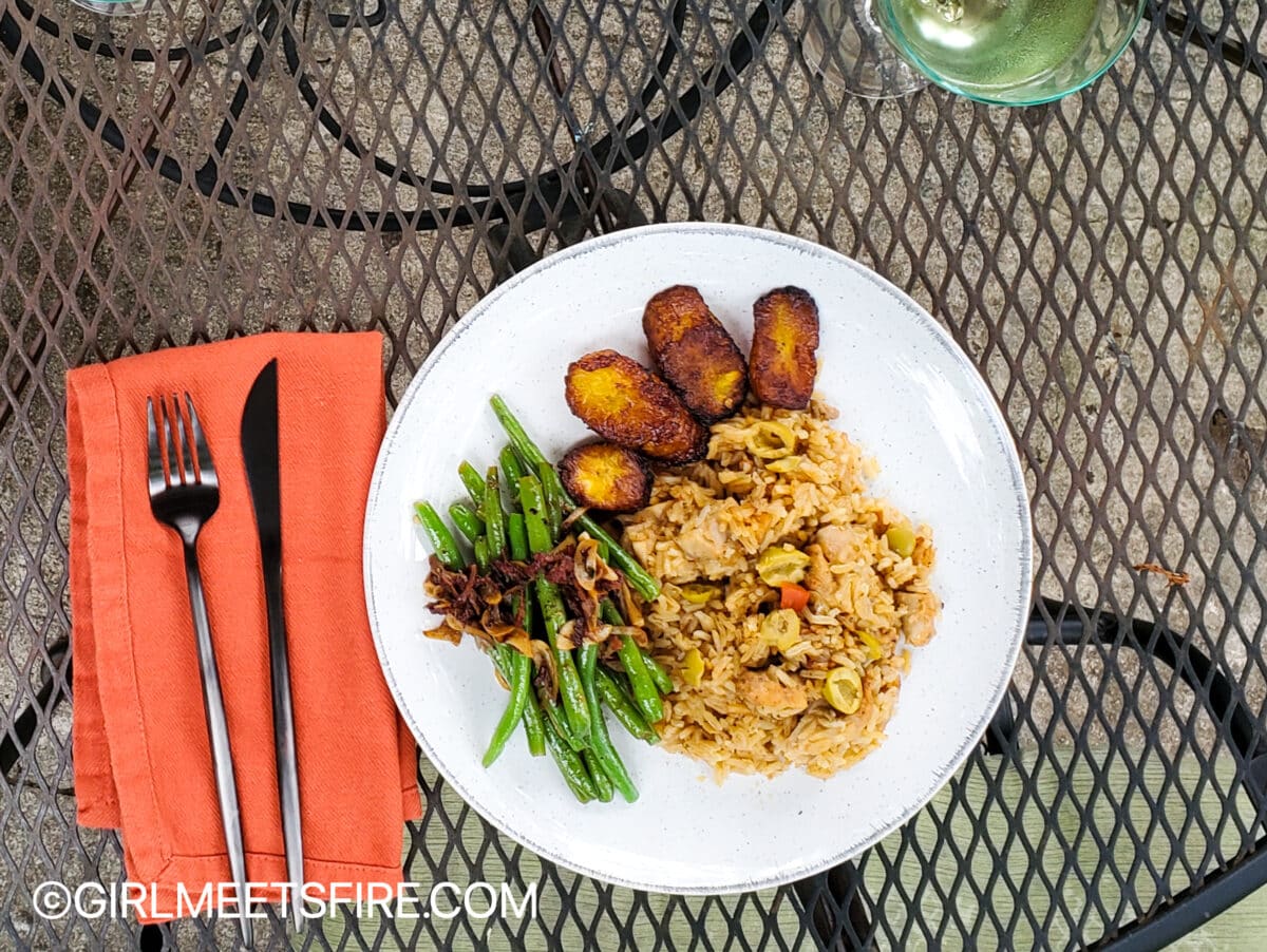 overhead picture of a plate of arroz con pollo served with green beens and pan fried ripe plantains.