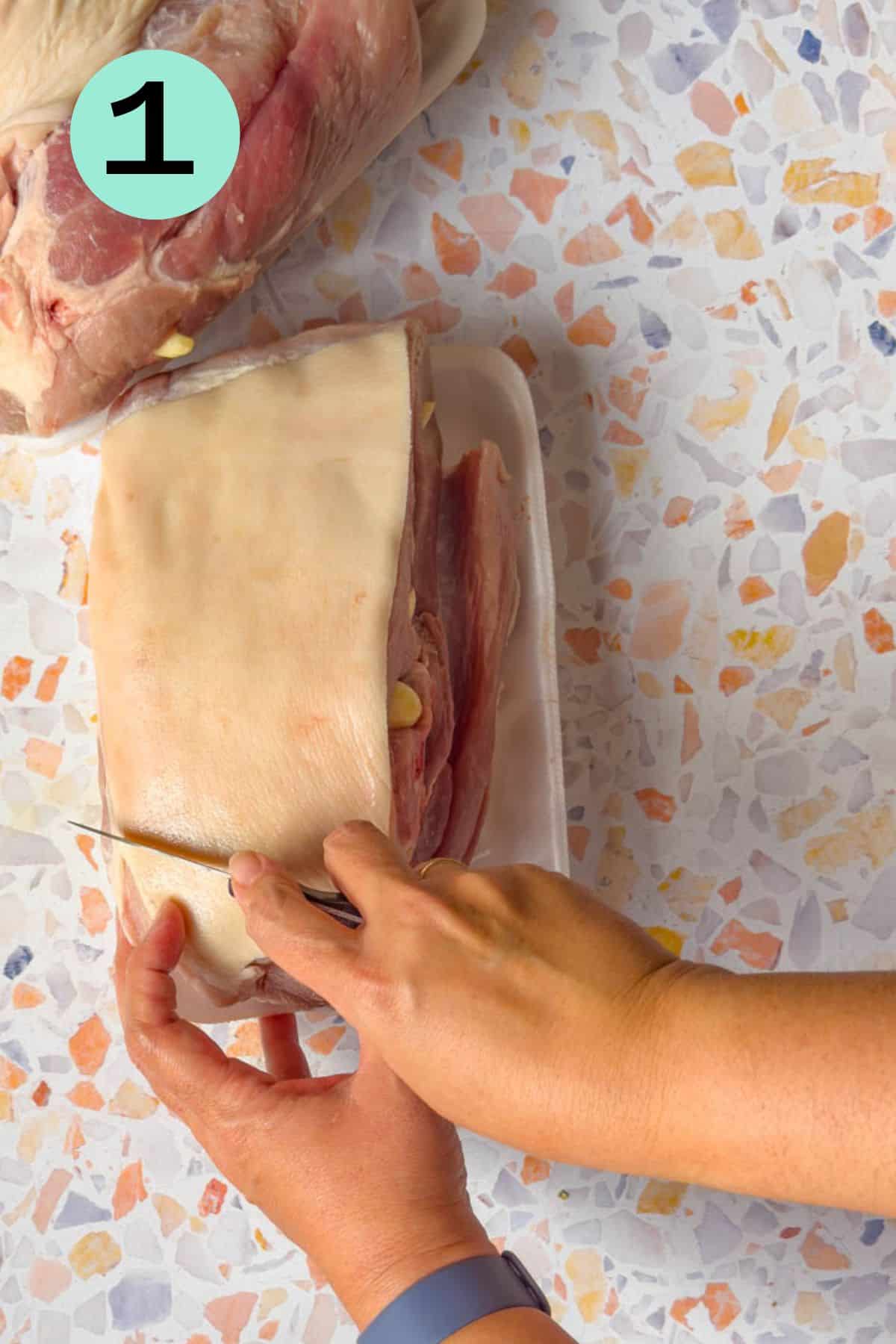 Scoring the skin of the pork roast with a sharp pairing knife.