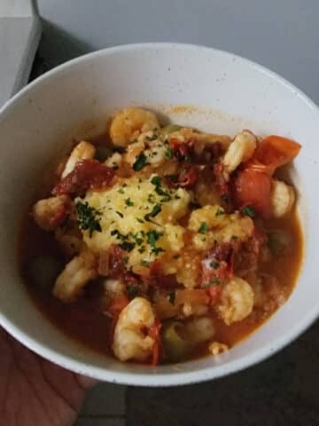 A bowl of funche with shrimp and tomato sauce