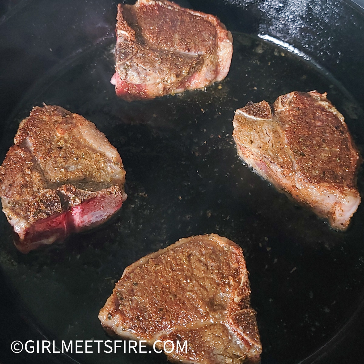 Lamb chops searing on a cast iron skillet