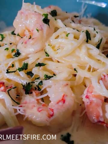 a close up of pasta with creamy sauce and shrimp