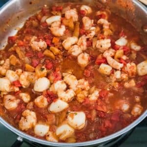 an image of pan stew with shrimp, scallops, and tomatoes.