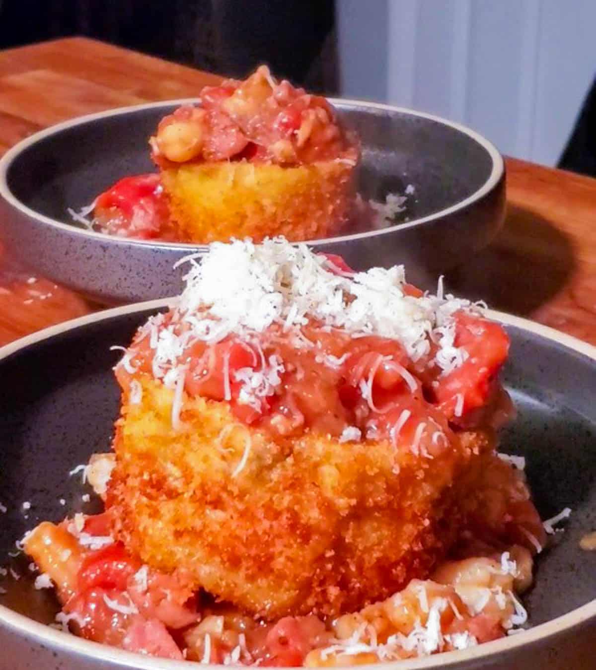 Two bowls with Crispy eggplant boats topped with shrimp stew and shredded parmesan cheese