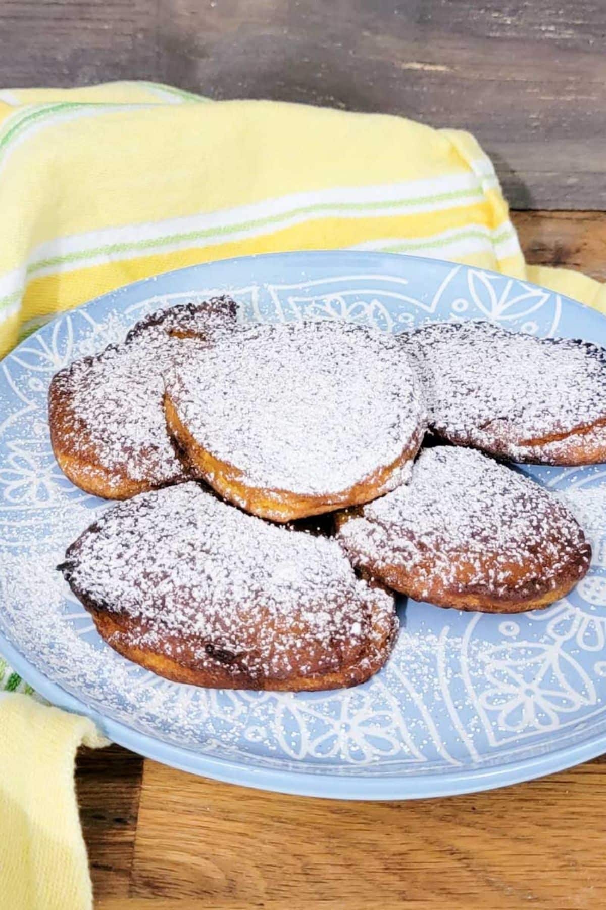 an image of a plate with pumpkin fritters or barriguitas de vieja, dusted with powdered sugar and cinnamon.