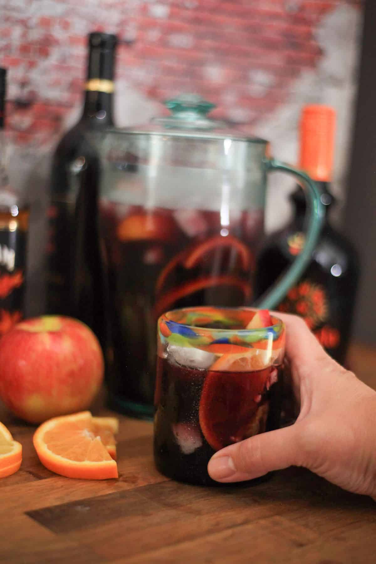 a hand reaching out to grab a glass of sangria