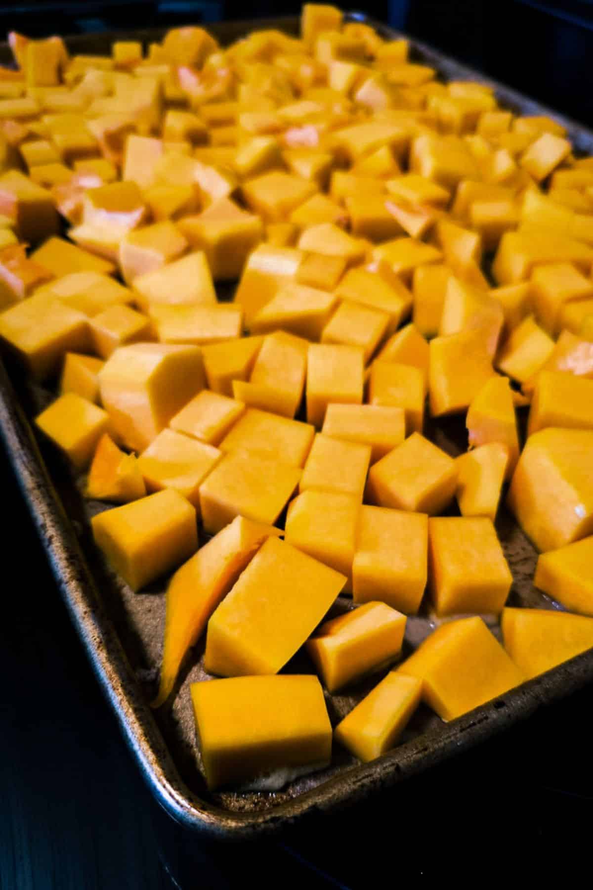 Image of butternut squash on a baking sheet pan before going into the oven.