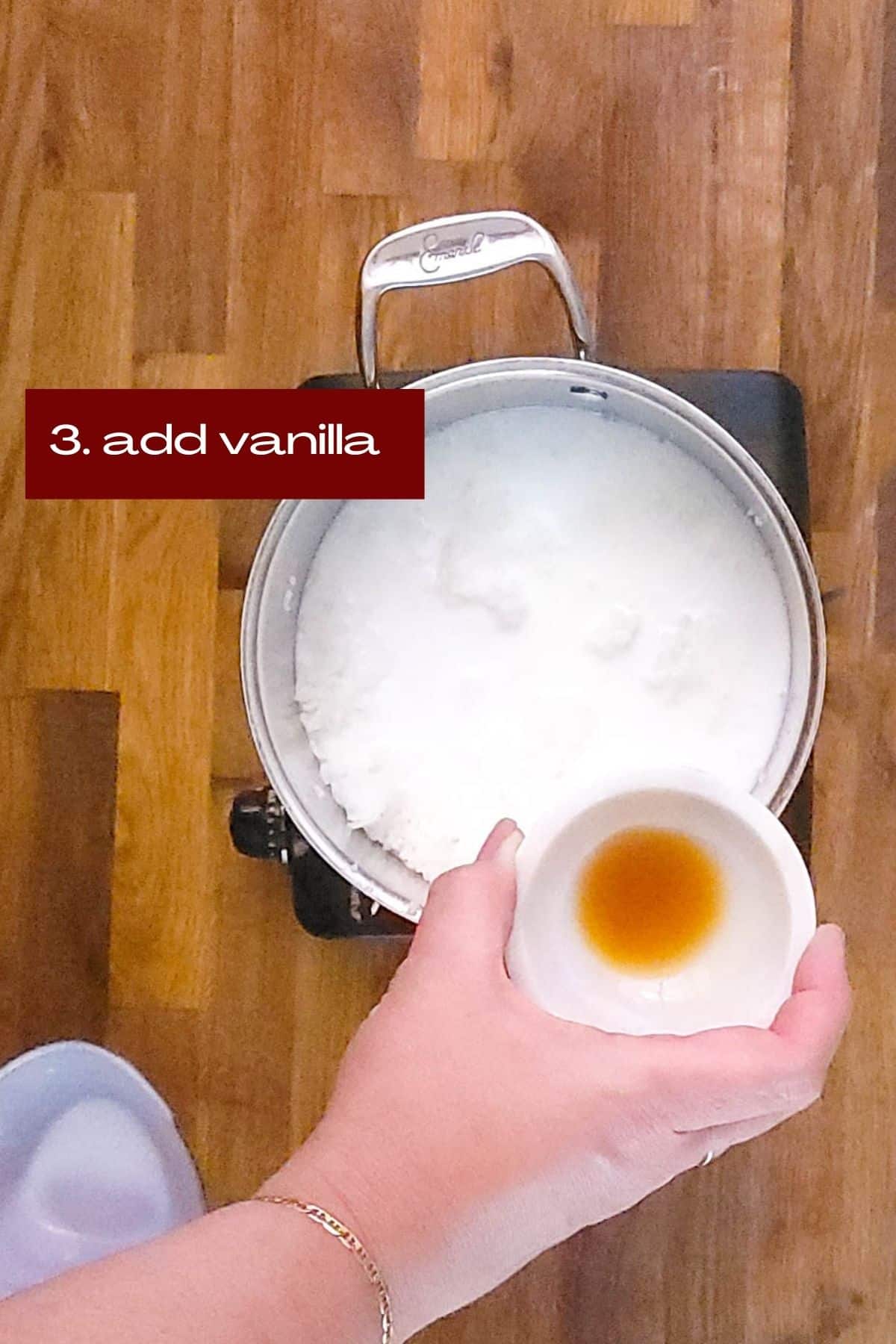 A sauce pan with cooked rice, milk, coconut milk, and now adding a tablespoon of vanilla.