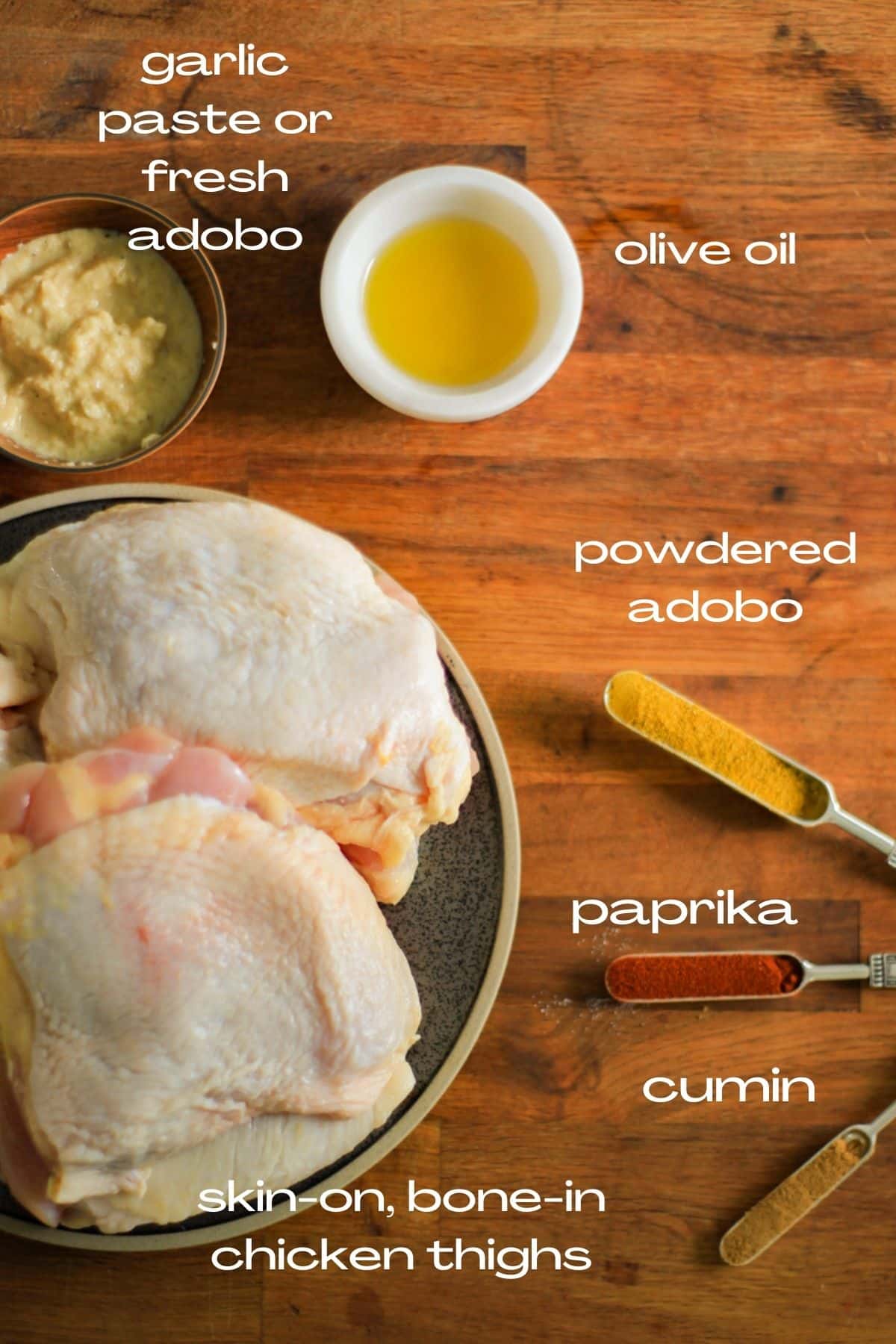ingredients for roasted chicken thighs: garlic paste or fresh adobo, olive oil, powdered adobo, paprika, cumin, skin on chicken thighs.