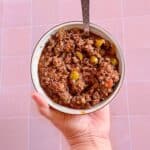 A bowl of picadillo with pieces of green olives, onions, capers, and pimentos mixed throughout.