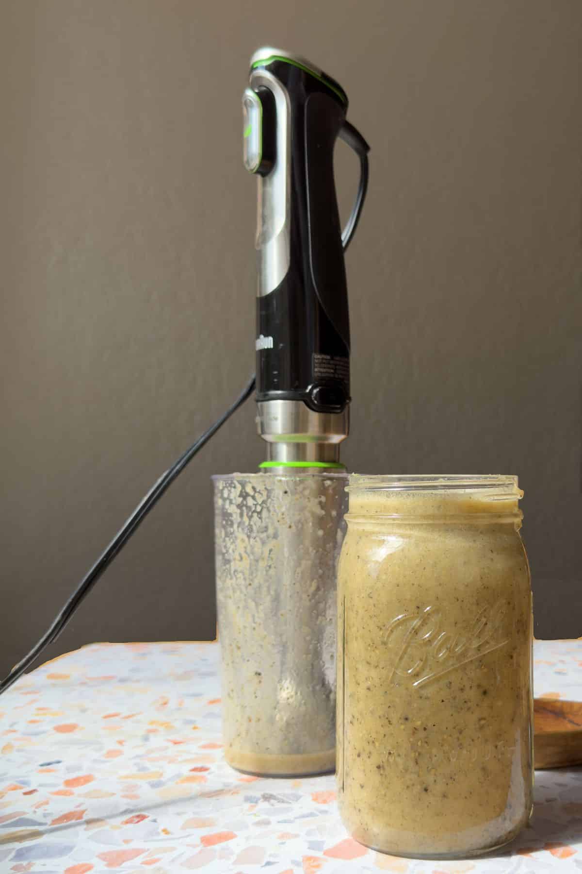 a terrazo top table with a jar of freshly made mojo marinade. Immersion blender used to make it is sitting behind the mason jar.