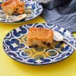 A blue and white dessert plate with a slice of bread pudding and caramel sauce on top of it.