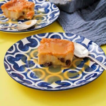 A blue and white dessert plate with a slice of bread pudding and caramel sauce on top of it.