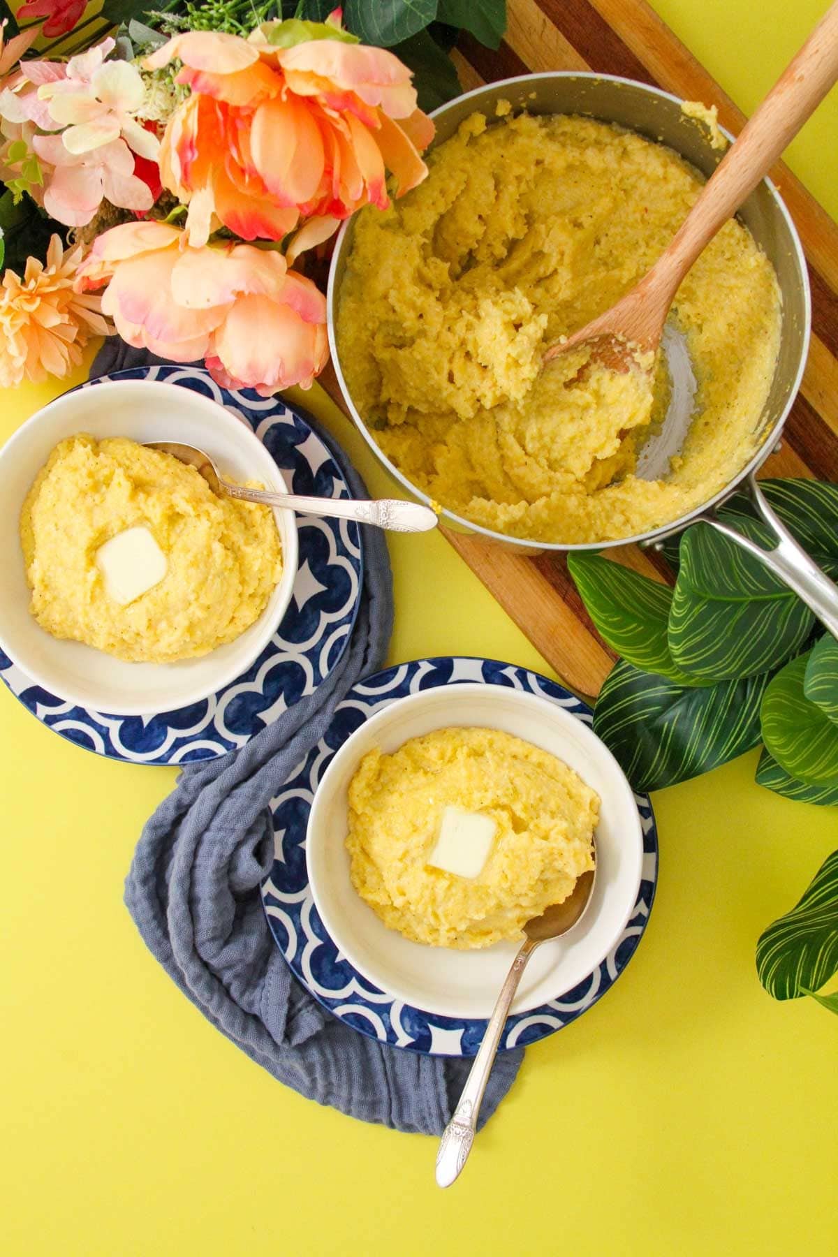 A table was served with two bowls of funche, two dabs of butter, a pot of funche, and a wooden spoon.