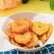 A paper towel-lined bowl of crispy tostones sprinkled with garlic salt.