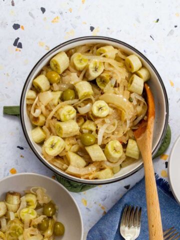 Guineitos en escabeche served in a bowl with onions and green olives, a traditional Puerto Rican green banana salad