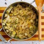 Sliced green bananas mixed with escabeche sauce of onions, olives, and vinegar in a pot