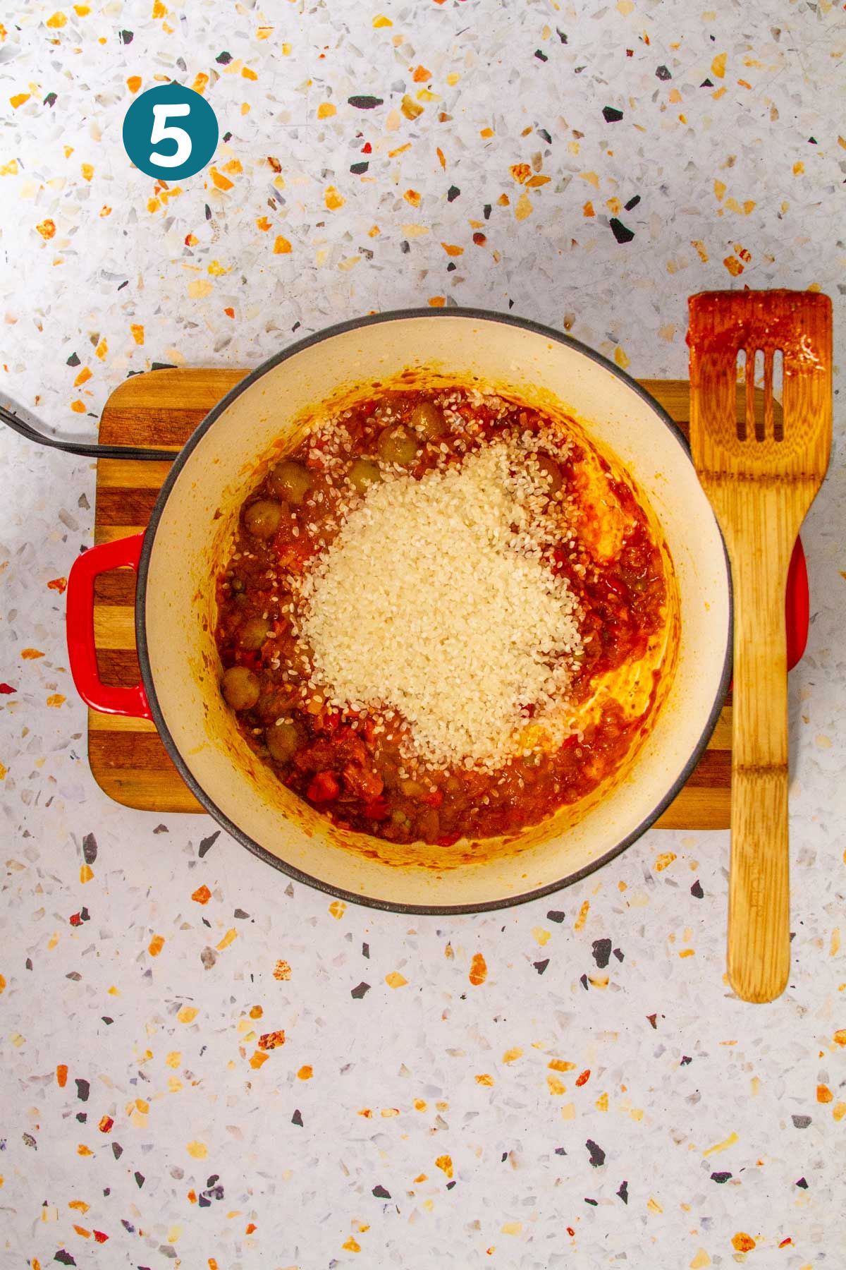 Uncooked medium-grain rice is poured over the crab and sofrito mixture.