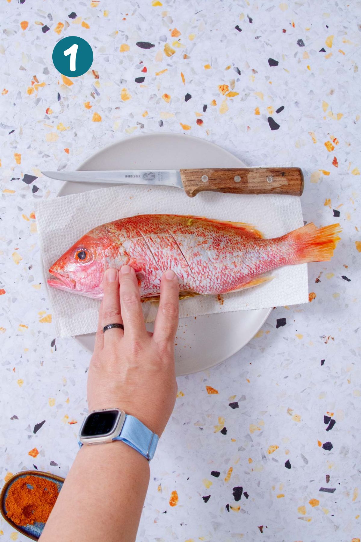 Scoring whole red snapper with a knife before seasoning for Puerto Rican fried fish.