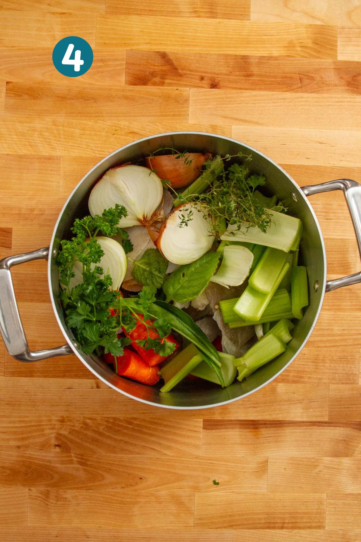 Fresh herbs, such as oregano brujo, culantro, parsley, and thyme, are added to the pot along with the vegetables and fish heads.