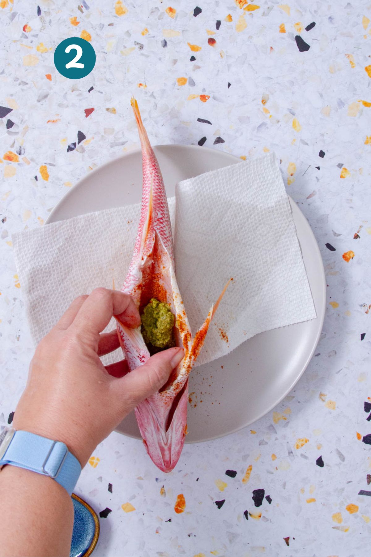 Stuffing red snapper cavity with sofrito and adobo before frying.