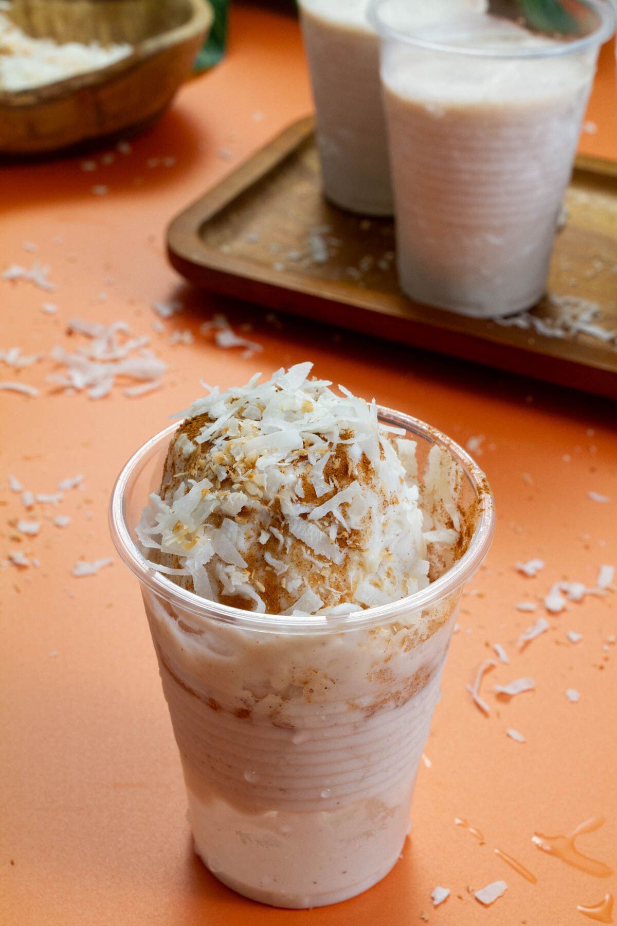 A detailed view of a Limber de Coco sprinkled with cinnamon and coconut flakes, set on an orange surface.