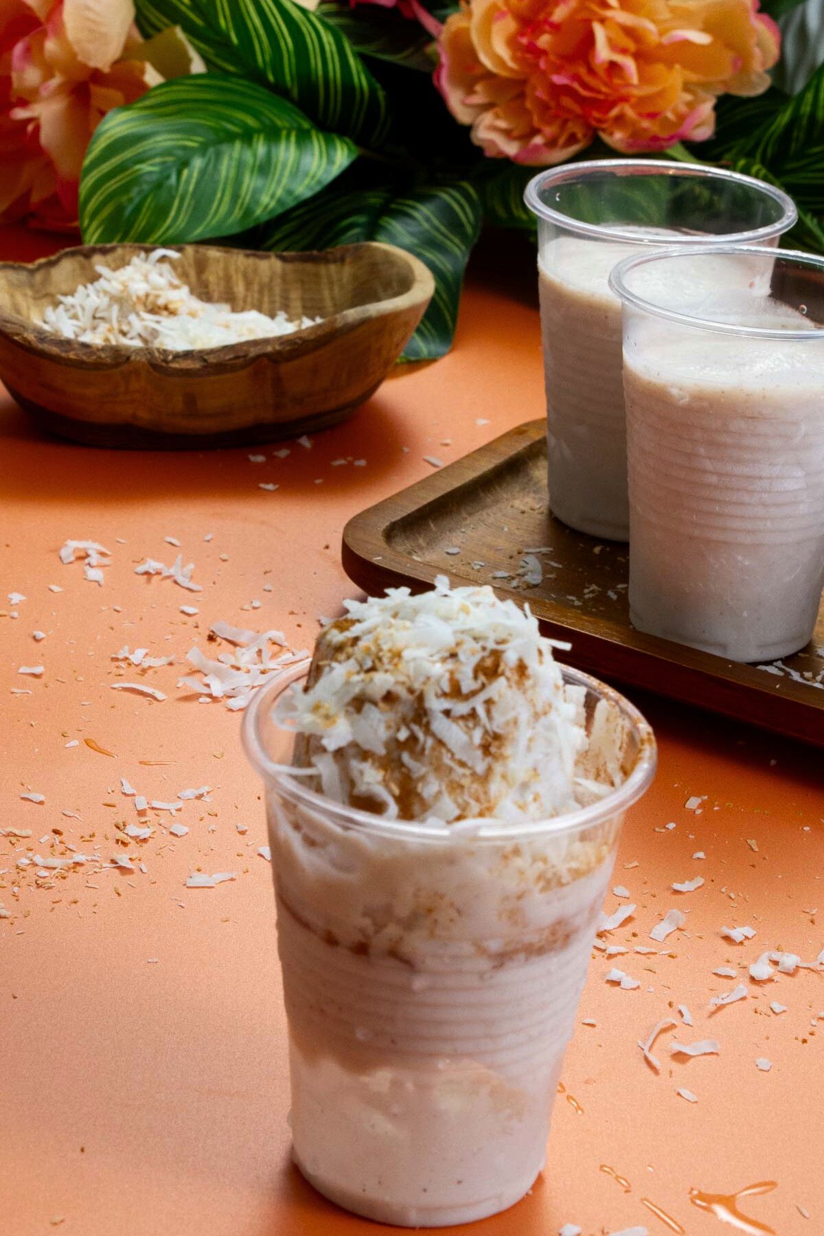 Limber de Coco served in a plastic cup with visible layers of cinnamon and coconut shreds, surrounded by tropical decor.