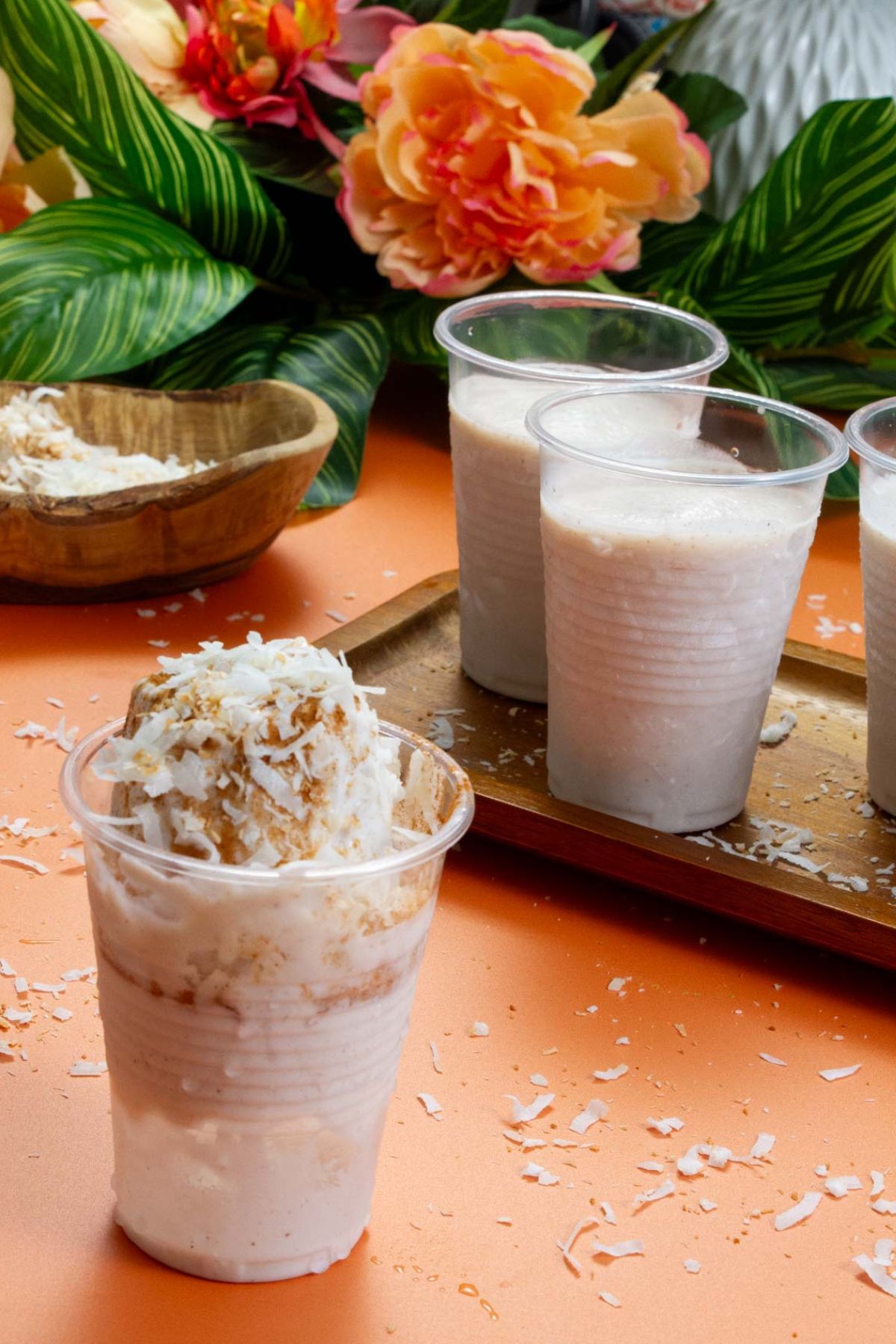 Hero shot of Limber de Coco surrounded by tropical flowers, wooden bowls, and a tray of frozen coconut ice pops.
