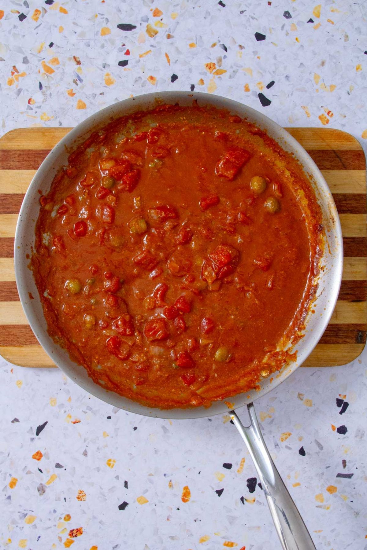 Mojo Isleño sauce simmering in a skillet, rich with tomatoes and olives, ready to serve.