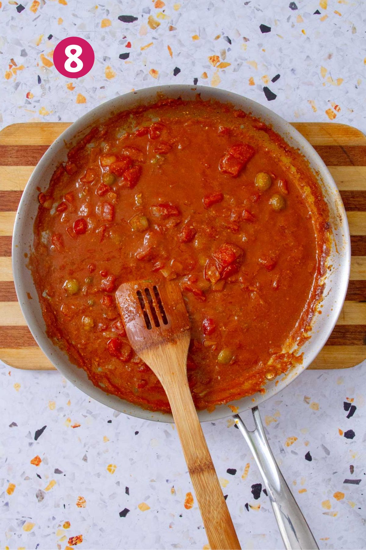 Finished Mojo Isleño sauce in a skillet, thickened and glistening with olives and tomatoes.