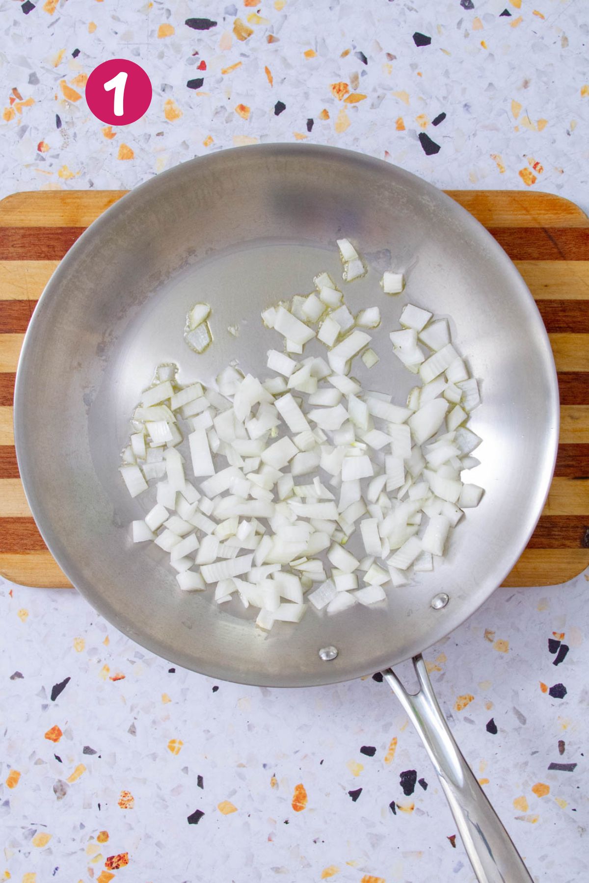 Onions are being sautéed in a skillet at the beginning stage of making Mojo Isleño.