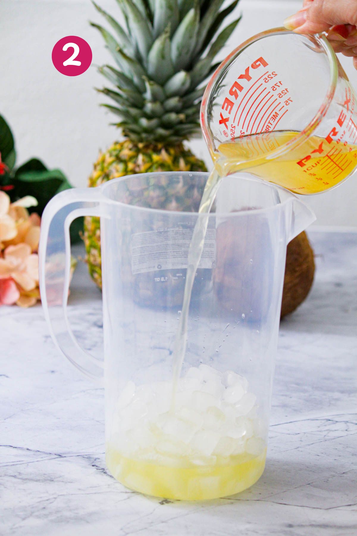Pouring pineapple juice from a measuring cup into a pitcher filled with ice.
