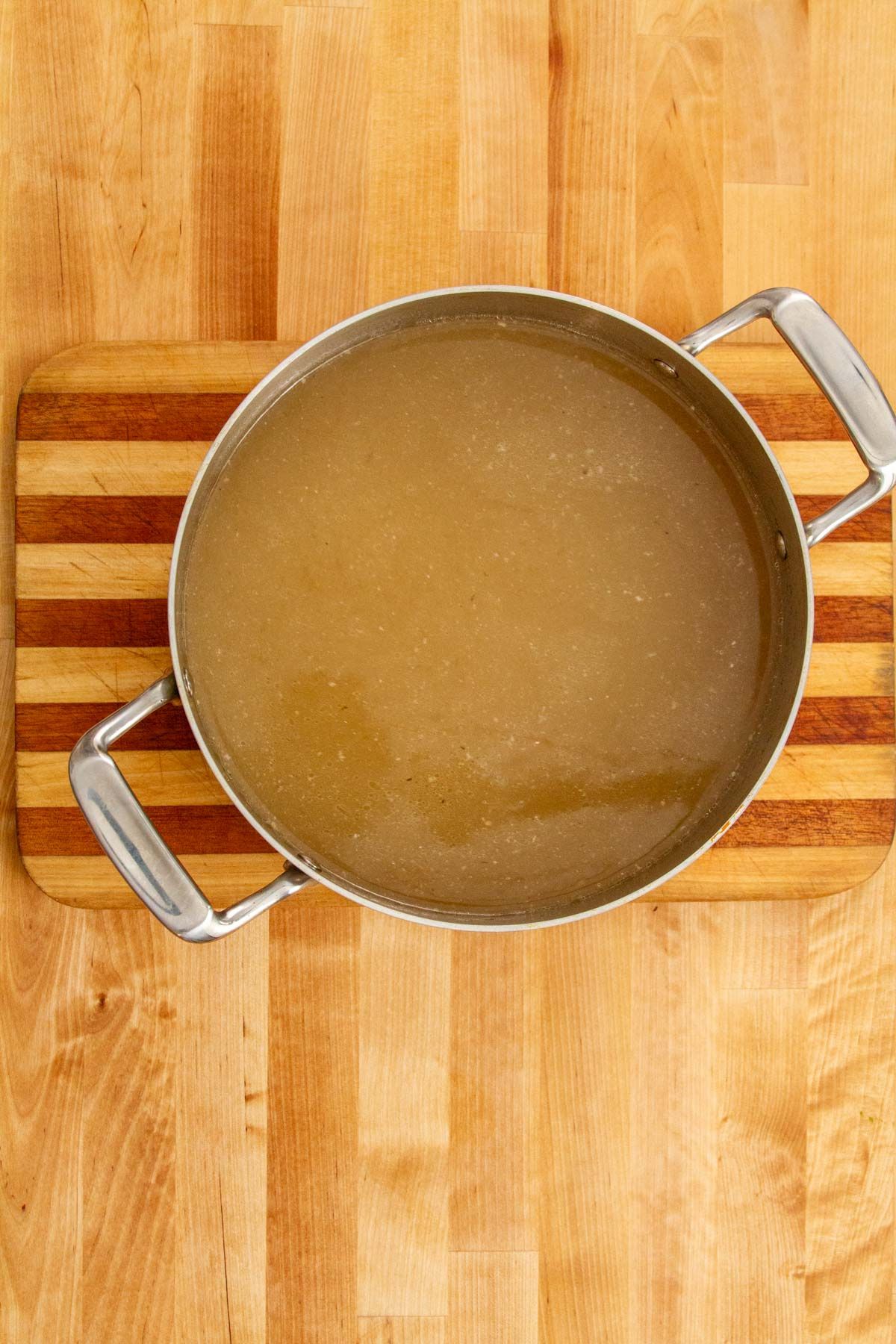 Finished Puerto Rican fish broth in a large pot, showing its golden, clarified appearance after straining.
