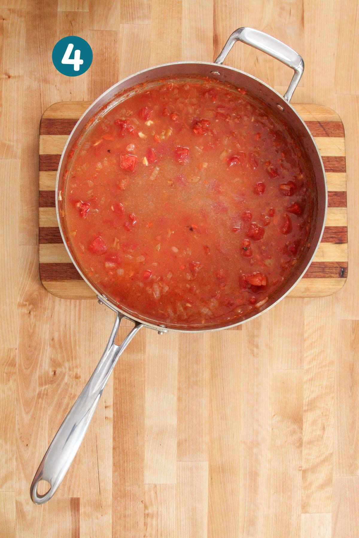 Tomato sauce is simmering in a skillet with white wine and fish broth added.