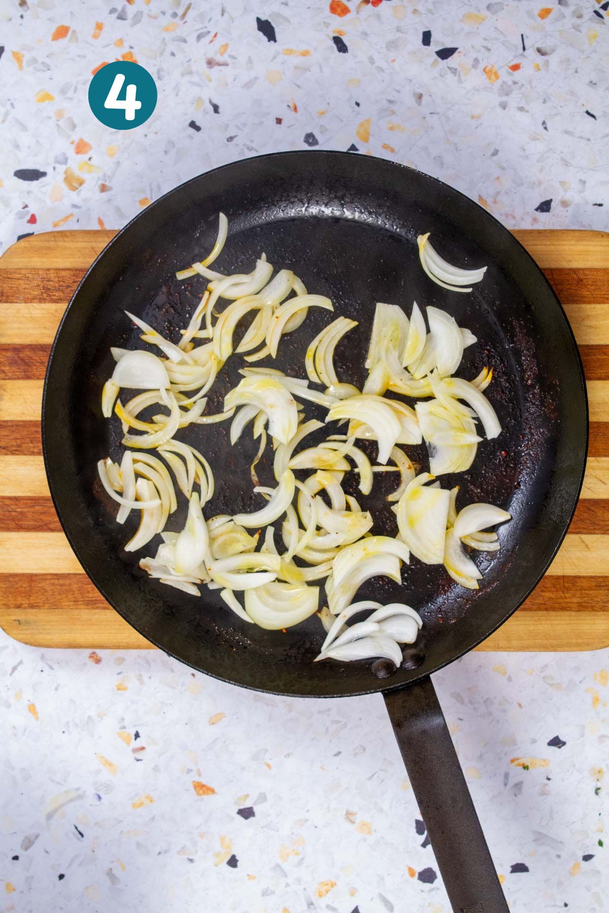 Sliced onions caramelizing in a sauté pan for biftec encebollado.