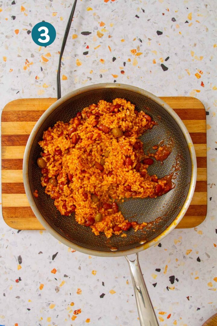 Skillet of arroz mamposteao with rice, beans, and olives fully mixed together.