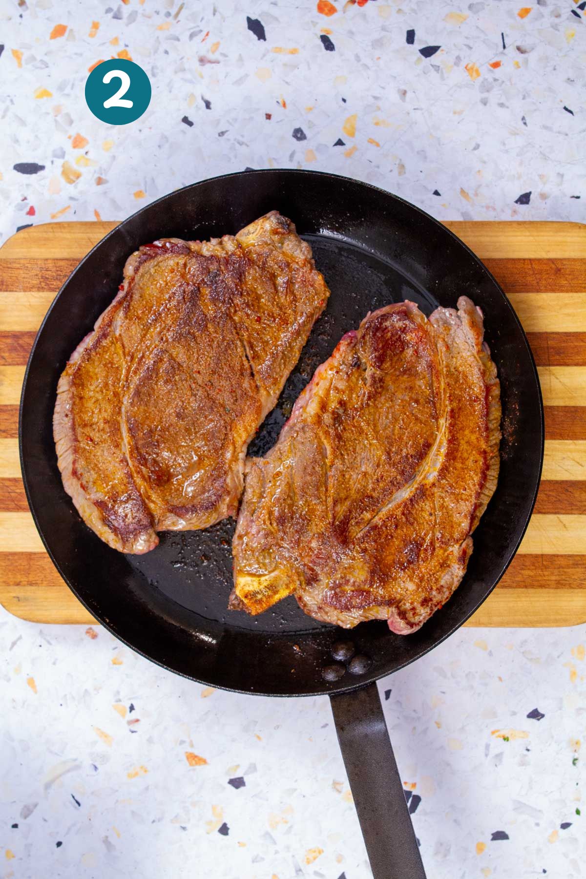 Thin-cut steaks are flipped to sear on the other side in a hot sauté pan.