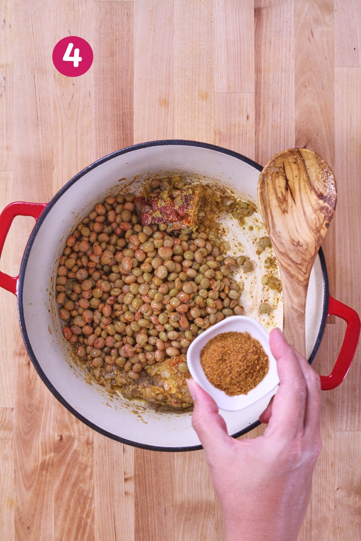 Cooked pigeon peas added to the pot along with seasoning, mixing into the sofrito, onion, and ham mixture.