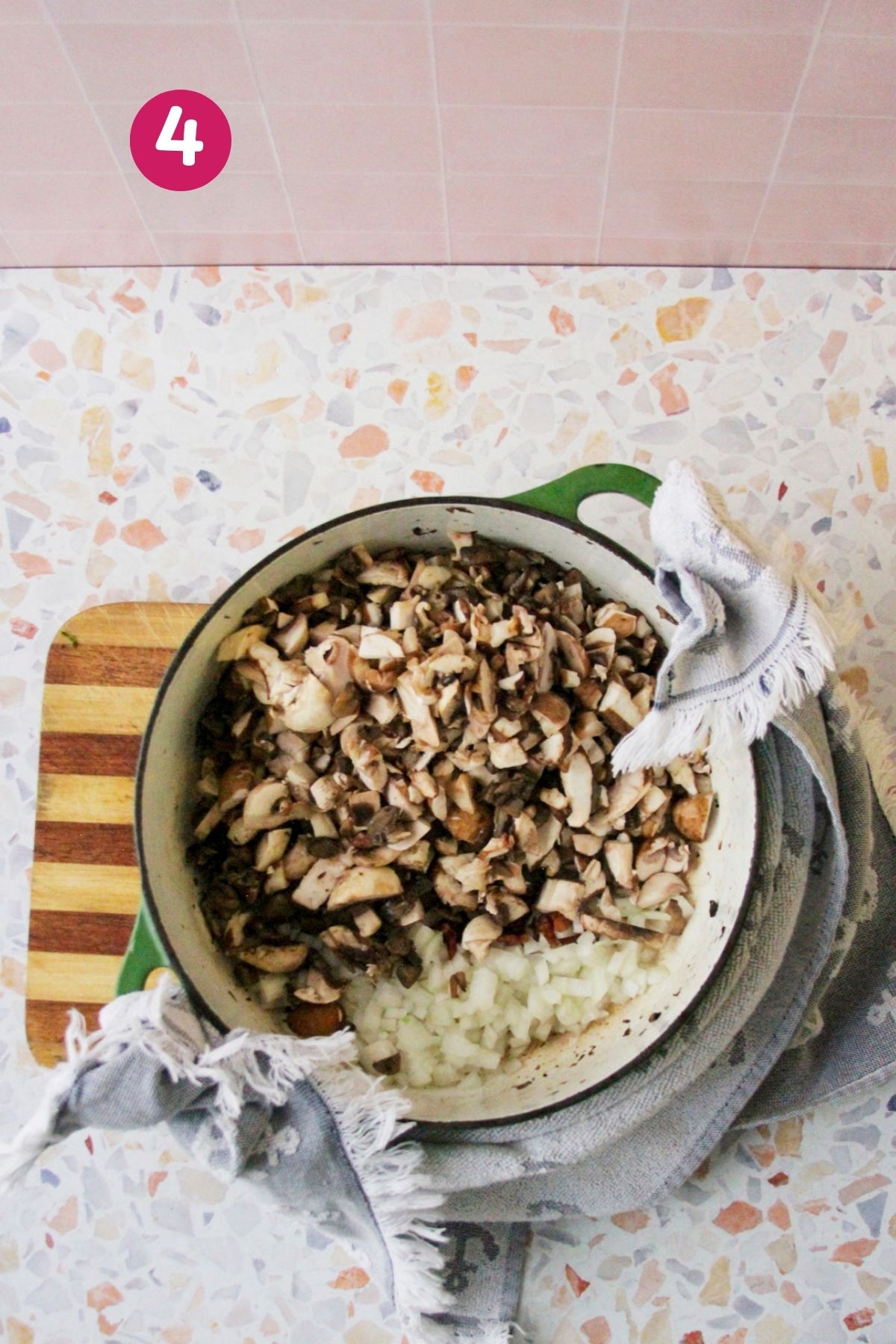 Chopped mushrooms and diced onions added to a Dutch oven with cooked bacon, photographed from overhead.