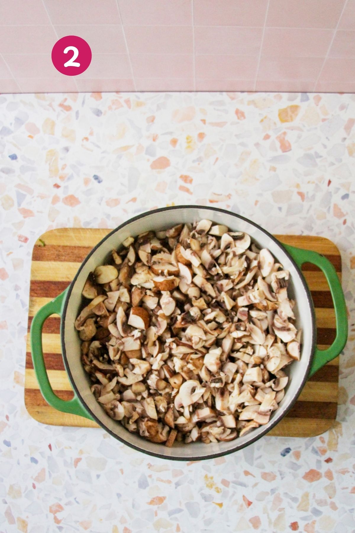 Mushrooms simmering in broth inside a Dutch oven as the soup cooks down, photographed from overhead.