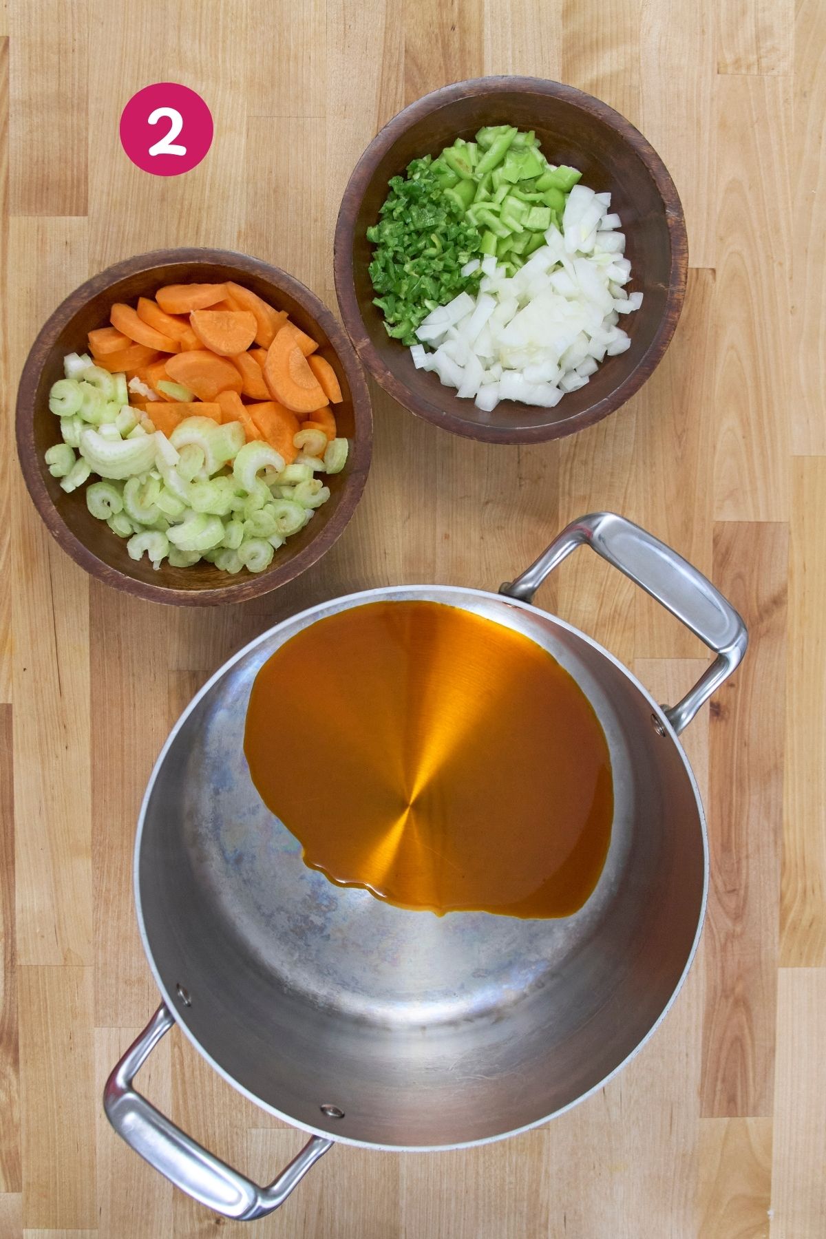Bowls of chopped carrots, celery, onions, and green peppers arranged on a wooden surface.