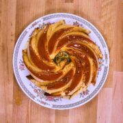 Overhead view of whole flancocho on vintage floral plate showing distinctive bundt pattern with glossy caramel sauce coating.