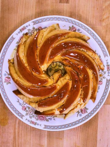 Overhead view of whole flancocho on vintage floral plate showing distinctive bundt pattern with glossy caramel sauce coating.