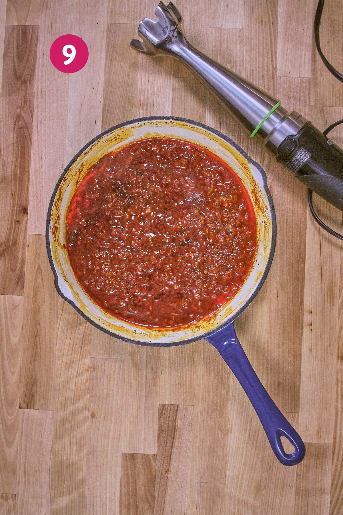 Overhead view of smooth blended brava sauce in skillet with immersion blender beside it, labeled with step 9.
