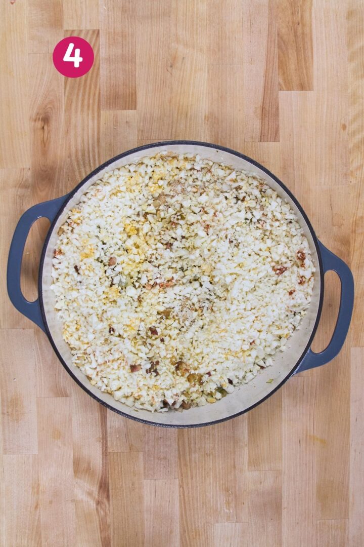 Overhead view of cauliflower rice sautéing with diced onions and bacon pieces in braiser, labeled with step 4.