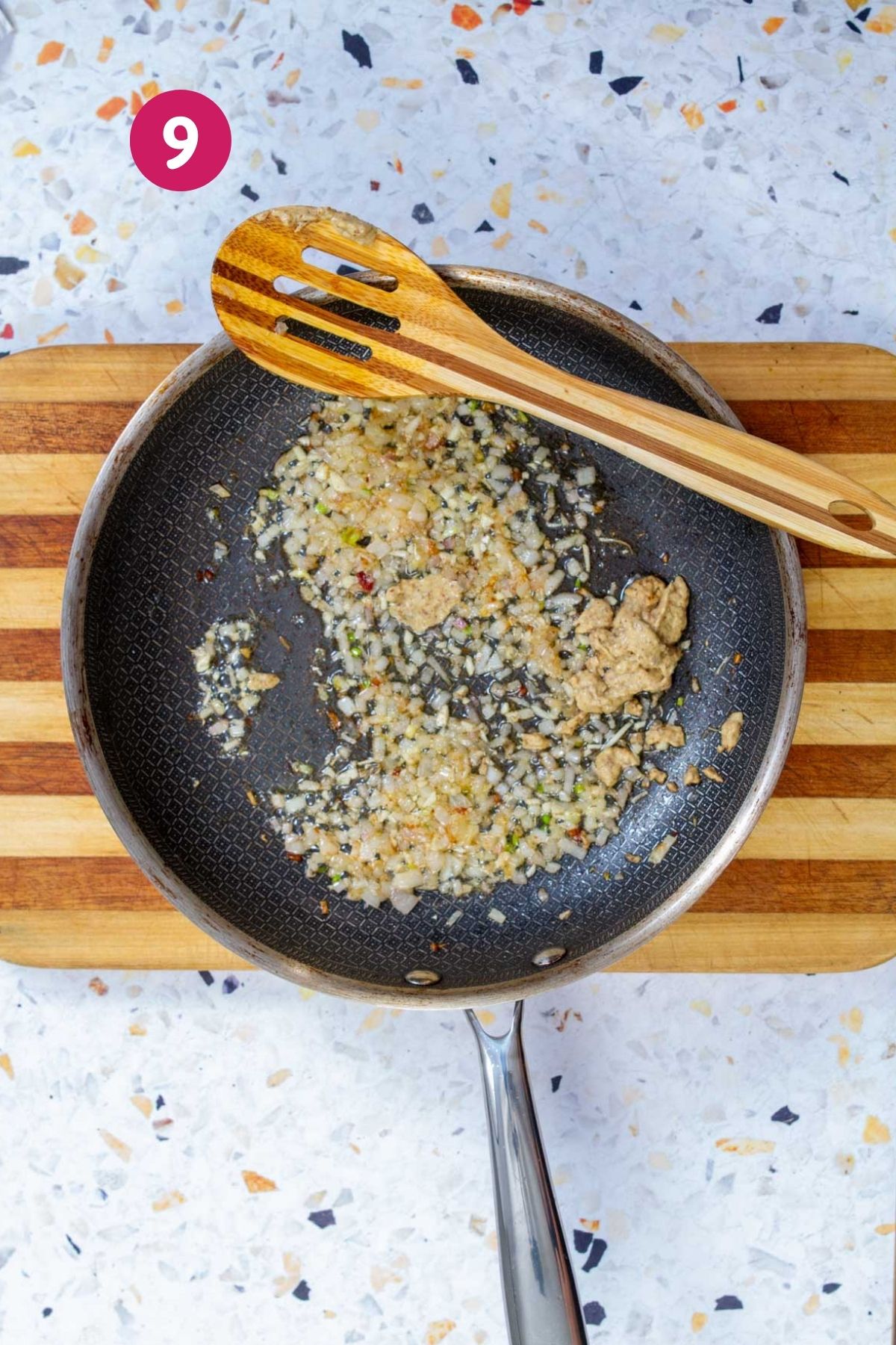 Sautéed shallots with mustard added to bacon fat in a nonstick skillet for yuca salad vinaigrette.