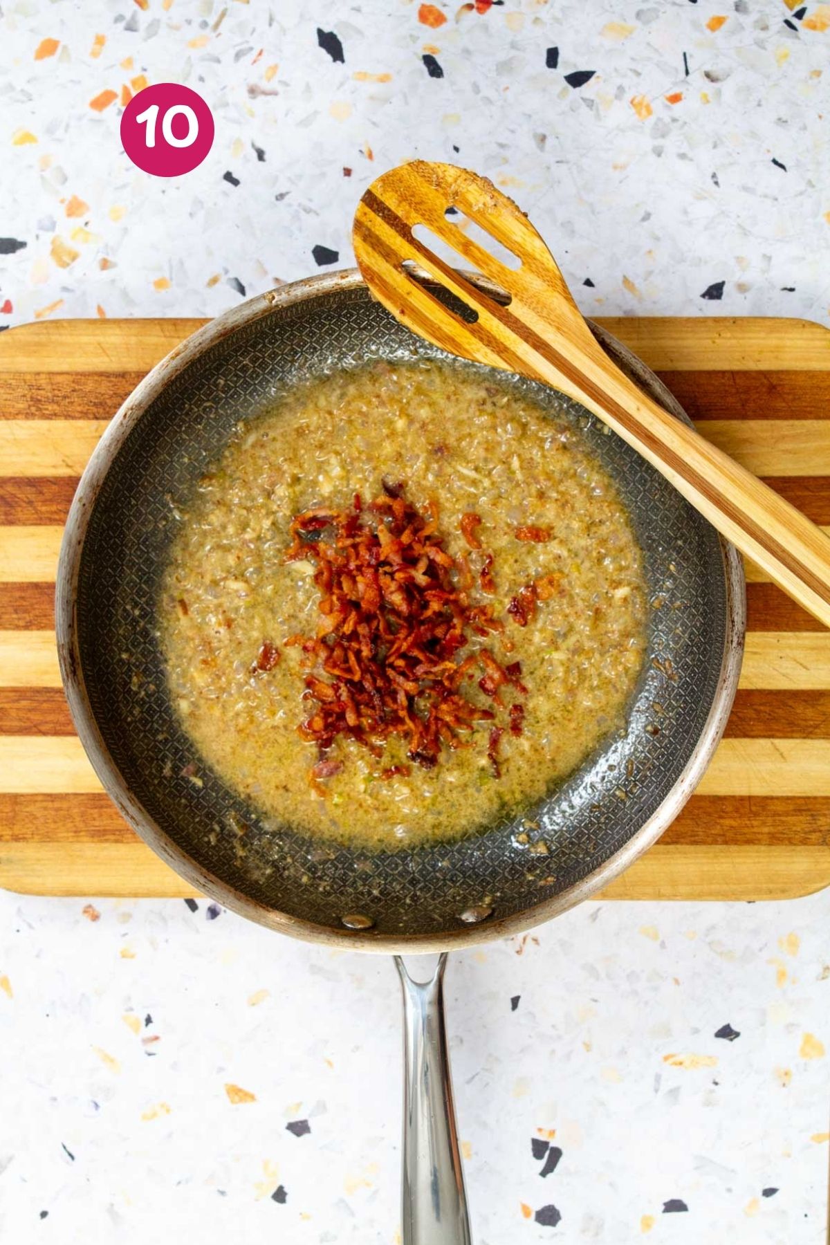 Bacon vinaigrette with shallots, mustard, and bacon pieces bubbling in a nonstick skillet.