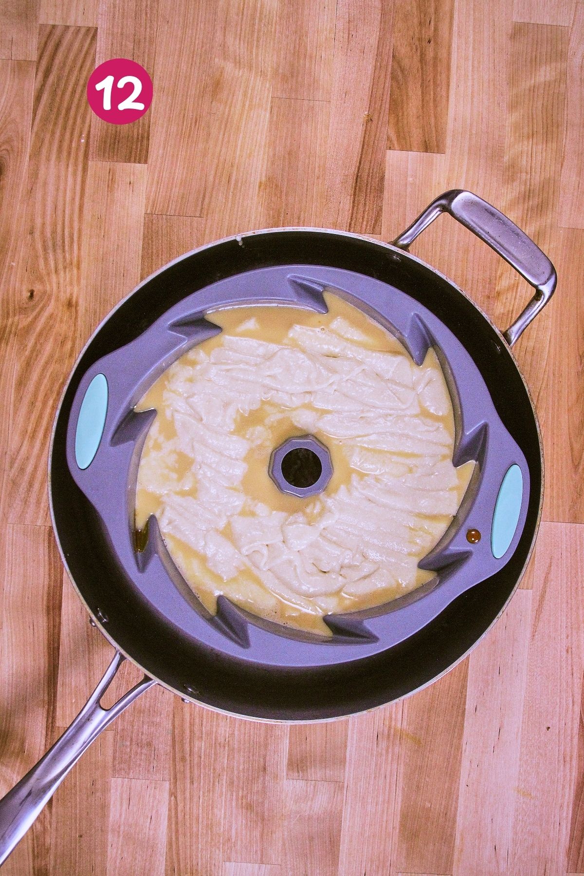 Cake batter poured over flan custard in a silicone bundt mold set inside a braiser, ready for the water bath and oven.