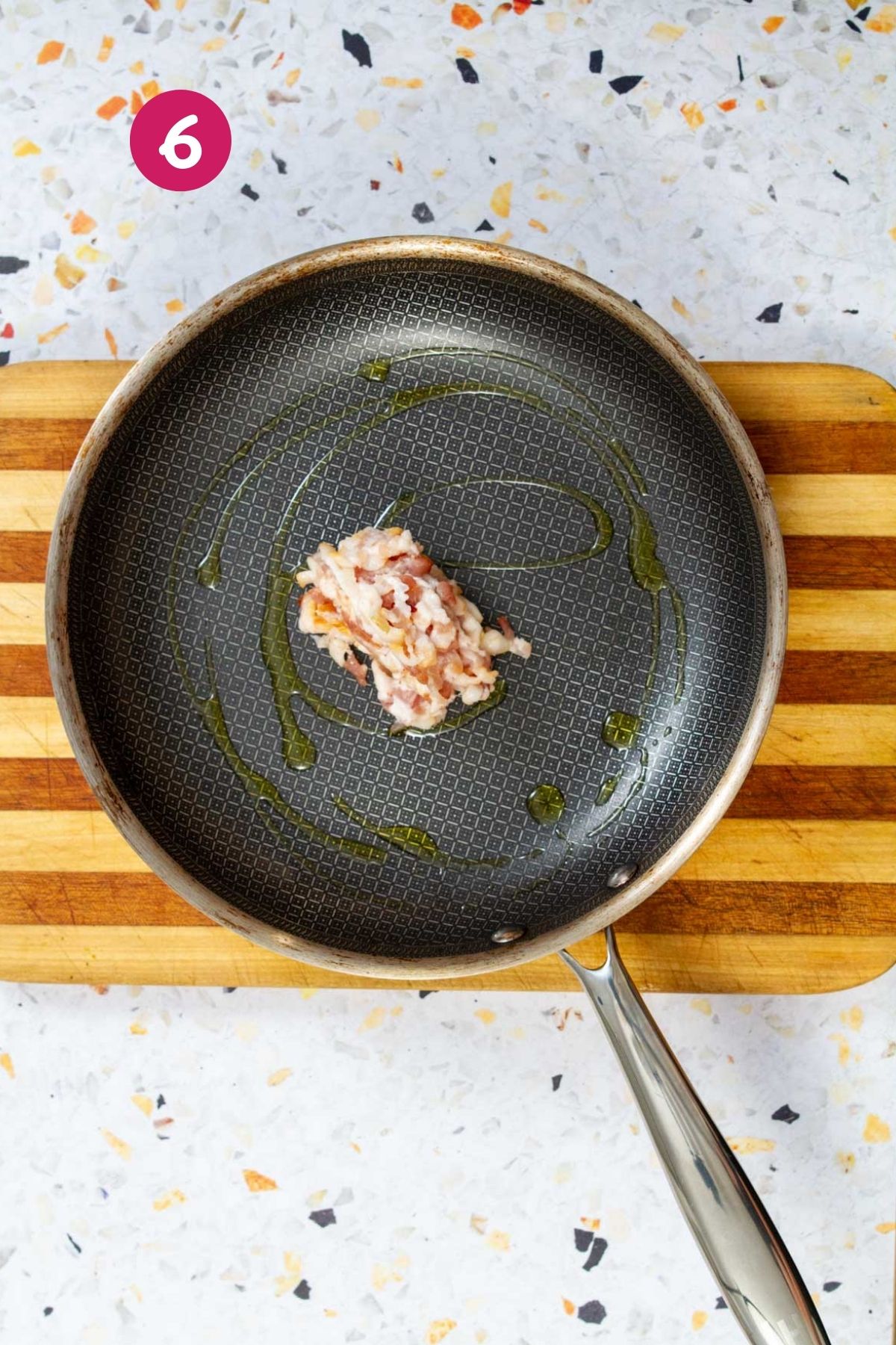 Chopped bacon rendering in a nonstick skillet with bacon fat collecting in the pan.