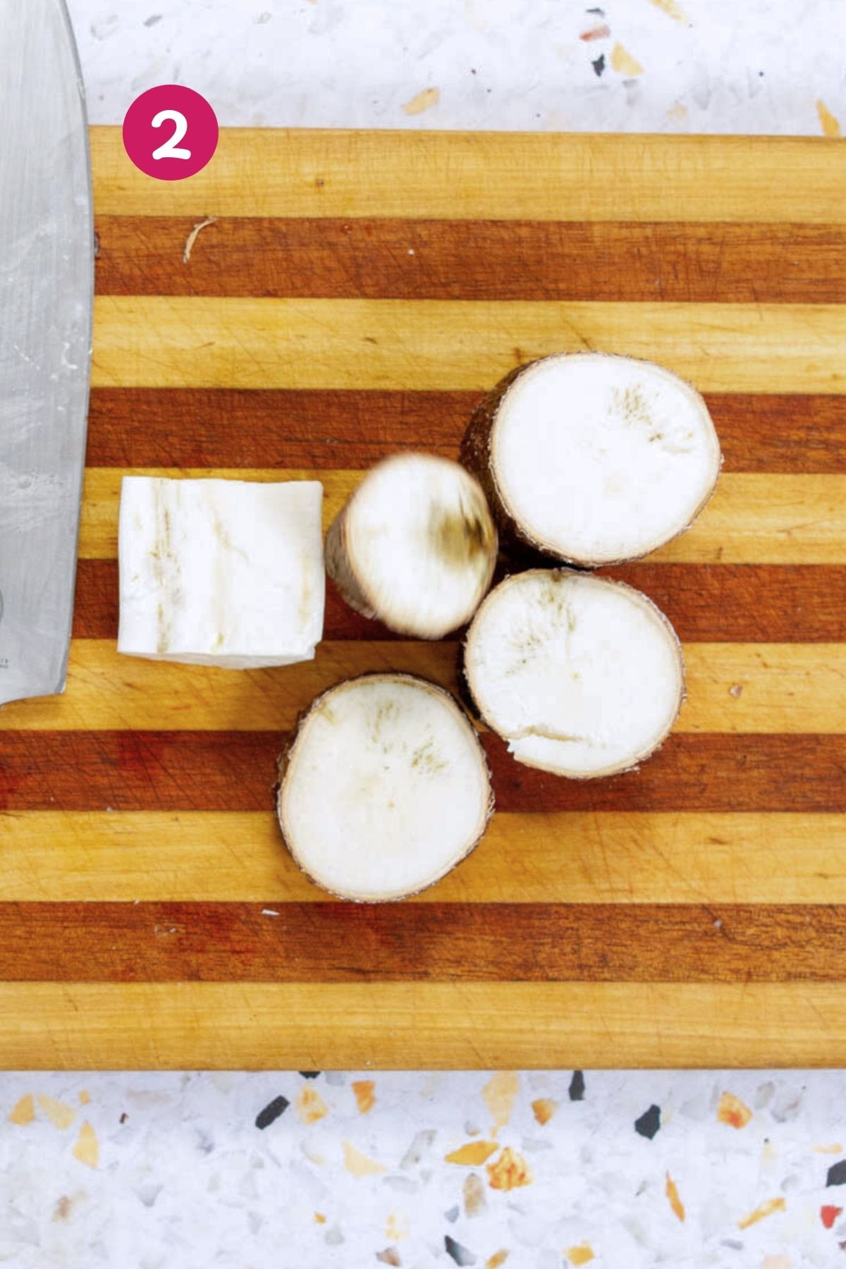 Cross-section of yuca root showing good white flesh and darker discolored sections indicating quality on a wooden cutting board.