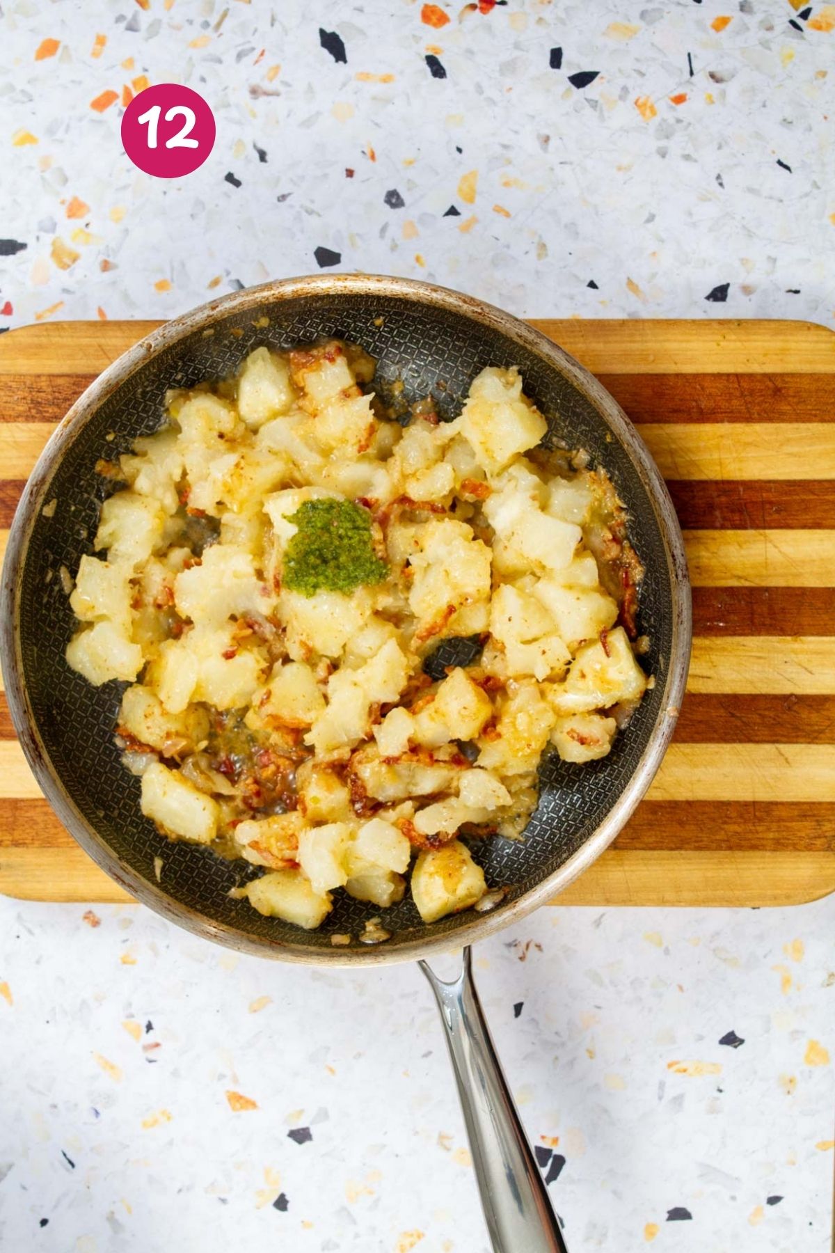 Tossing cubed yuca with bacon vinaigrette and green sofrito in a nonstick skillet with wooden serving spoons.